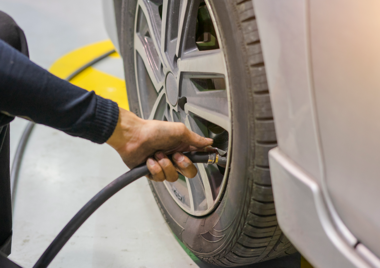 Person inflating car tire with air hose.